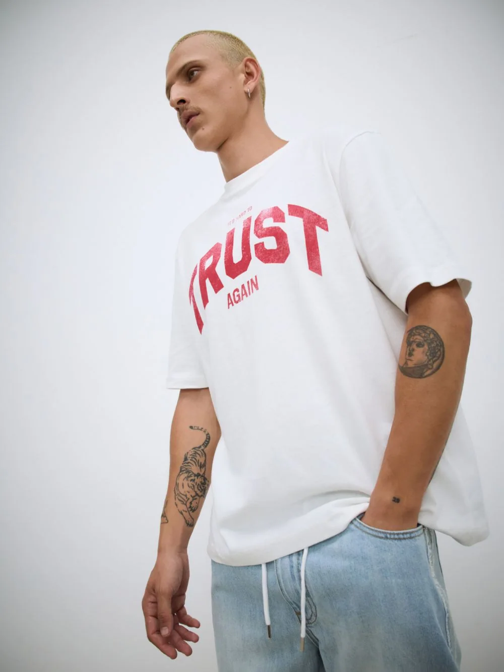 חולצה לבנה עם הדפס TRUST באדום, צילום מזווית נמוכה